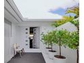 Inviting front entrance with white decor, potted trees and stylish door with square windows at 440 64Th Ave, St Pete Beach, FL 33706