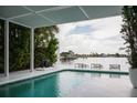 Inviting pool area with a covered patio, waterfront views, and stylish lounge chairs for relaxation and enjoying the scenery at 440 64Th Ave, St Pete Beach, FL 33706