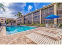 Relaxing pool area surrounded by lounge chairs and tropical landscaping with building in the background at 465 Pinellas Bayway S # 307, Tierra Verde, FL 33715