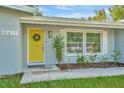 House exterior featuring a yellow front door and lovely landscaping at 10617 N 27Th St, Tampa, FL 33612