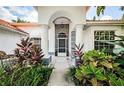 A home's grand front entrance features white pillars and lush, colorful landscaping at 441 Village Dr, Tarpon Springs, FL 34689