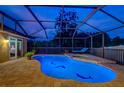 Luminous night view of a screened pool and spa with dolphin accents at 957 Westwinds Blvd, Tarpon Springs, FL 34689