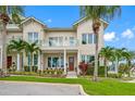 Two-story home with a light beige facade, front porch, and lush landscaping at 6 Hibiscus Ln, Belleair, FL 33756