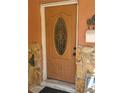 Front door with an oval glass design and oak wood finish at 8665 Mockingbird Ln, Seminole, FL 33777