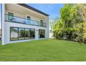 Beautiful backyard with glass-paneled balcony, sliding glass doors, lush green lawn and tropical landscaping at 2721 17Th N Ave, St Petersburg, FL 33713