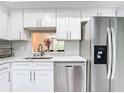 Modern kitchen with stainless steel appliances, white cabinets, a stylish backsplash, and a well-lit workspace at 1433 S Belcher Rd # G10, Clearwater, FL 33764