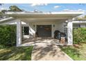 Covered porch with gray double doors and fall decor at 10208 Grove Dr, Port Richey, FL 34668