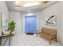 Bright entry with blue doors, wood bench, and tile floors at 1 Seaside Ln # 104, Belleair, FL 33756