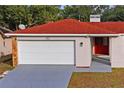 House exterior showcasing a red tile roof, white garage door, and red front door at 2502 Indigo Dr, Dunedin, FL 34698