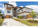 Stunning modern home featuring a two-car garage, stone accents, and lush landscaping with a vibrant green lawn at 2121 Bayou Grande Ne Blvd, St Petersburg, FL 33703