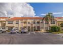 Two-story condo building with a tile roof, palm trees, and parking in front at 6141 Bahia Del Mar Blvd # 232, St Petersburg, FL 33715