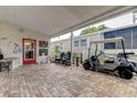 Brick-paved patio with covered area, seating, and golf cart at 192 Blue Marlin Dr, Oldsmar, FL 34677