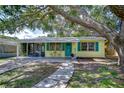 Inviting single-story home with a quaint front porch, blue shutters, and lush landscaping, perfect for relaxation at 5210 Newton S Ave, Gulfport, FL 33707