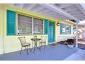 Cozy front porch with seating, vibrant blue door, and bright yellow exterior, ideal for enjoying the outdoors at 5210 Newton S Ave, Gulfport, FL 33707