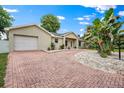 Inviting single-story home featuring an attached garage and a red brick driveway at 1740 51St N St, St Petersburg, FL 33710
