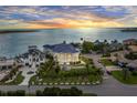 Stunning aerial view of waterfront estate with lush landscaping, circular driveway, and breathtaking sunset backdrop at 774 Nina Dr, Tierra Verde, FL 33715