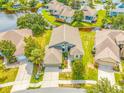 Aerial view of a single-Gathering home with a landscaped yard and a nearby lake at 1008 Blue Heron Way, Tarpon Springs, FL 34689