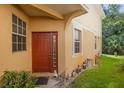 Townhome's front entrance with orange door and garden decor at 1938 Fiesta Ridge Ct, Tampa, FL 33604