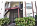 Condo building entry with stairs, a screened door, and lush landscaping at 3455 Countryside Blvd # 15, Clearwater, FL 33761