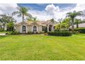 One-story house with tile roof, lush landscaping, and palm trees at 19003 Apian Way, Lutz, FL 33558