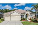 House exterior featuring a three-car garage, manicured lawn, and attractive landscaping at 22531 Eagles Watch Dr, Land O Lakes, FL 34639
