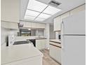 Condo kitchen with white cabinets, appliances, and wood-look floors at 1933 Golfview Dr # 1933, Tarpon Springs, FL 34689