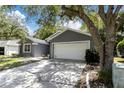 Gray house with white garage door and landscaping at 5204 New Brittany Ln, Zephyrhills, FL 33541