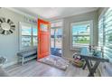Entryway with gray bench, orange door and wood-look floors at 142 Beach Ave, Redington Shores, FL 33708