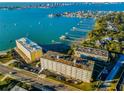Aerial view showing multiple buildings near the waterfront with boat docks and cityscape in the background at 100 Bluff View Dr # 405C, Belleair Bluffs, FL 33770