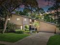 Charming two-story home at dusk with landscaped yard and a long driveway leading to the attached two-car garage at 3047 Enisglen Dr, Palm Harbor, FL 34683