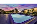 Inviting community pool at sunset with surrounding landscape lighting at 50 Coe Rd # 125, Belleair, FL 33756