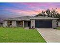 Charming single-story home featuring a well-manicured lawn and a two-car garage at dusk at 3067 Newbury St, Port Charlotte, FL 33952