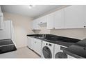 Efficient kitchen with white cabinetry, black granite countertops, stainless steel sink, and in-unit washer and dryer at 3211 W Swann Ave # 808, Tampa, FL 33609