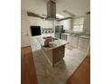 Bright kitchen with white cabinets, an island with cooktop, and stainless steel appliances at 3124 Pond Hollow St # 183, Wesley Chapel, FL 33543