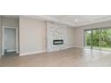 Bright open-plan living room with wood-look flooring, modern fireplace, and sliding glass doors to outside at 14362 San Domingo Blvd, Port Charlotte, FL 33981