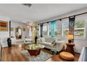 Bright living room featuring wood floors, a white sofa, and large windows with plantation shutters at 6012 1St W Ave, Bradenton, FL 34209
