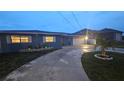 Charming home at dusk, illuminated by interior lights, features a concrete driveway and well-kept lawn at 3510 Magnolia Way, Punta Gorda, FL 33950