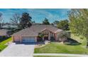One-story house with a driveway, landscaping, and a large backyard at 3473 Conifer Loop, Spring Hill, FL 34609