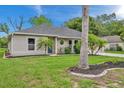 Tan house with gray roof, blue door, and palm trees in the front yard at 9007 Gibralter St, Spring Hill, FL 34608