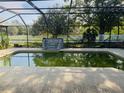 Screened-in pool area with decorative rock feature and view of the backyard's white picket fence at 6096 Kinlock Ave, Spring Hill, FL 34608