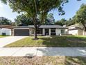 Newly renovated home with a modern facade and lush lawn at 6005 Soaring Ave, Temple Terrace, FL 33617