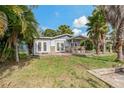 View of the home's backyard with patio, stonework and tropical landscaping at 9 Grace St, Crystal Beach, FL 34681