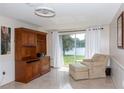 Bright living room with sliding glass doors leading to the lake, tiled floors and a comfortable armchair at 12307 Fieldstone Ln, Hudson, FL 34667