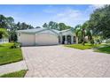 One-story house with a three-car garage and a large brick paver driveway at 34838 Arbor Green Pl, Zephyrhills, FL 33541