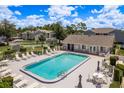 Community pool surrounded by lounge chairs and umbrellas, with nearby clubhouse, and bocce ball courts at 7712 Hillside Ct # 202, Hudson, FL 34667