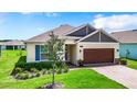 One-story home with a brown garage door, blue shutters, and landscaped lawn at 19492 Fort King Run, Brooksville, FL 34601