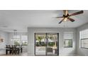 Bright, open living room with patio access, a ceiling fan, views to the backyard, and a dining area at 3893 Burdick Loop, Odessa, FL 33556