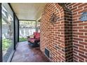 Enclosed patio features a red brick wall and a comfortable wicker seating area with a decorative 'stay awhile' pillow at 6635 Stewart N Ave, St Petersburg, FL 33702