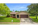 Tan one-story home with brown garage door at 7504 Cypress Knee Dr, Hudson, FL 34667