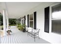 Front porch with white columns, black shutters and metal bench at 23337 Lake Lindsey Rd, Brooksville, FL 34601